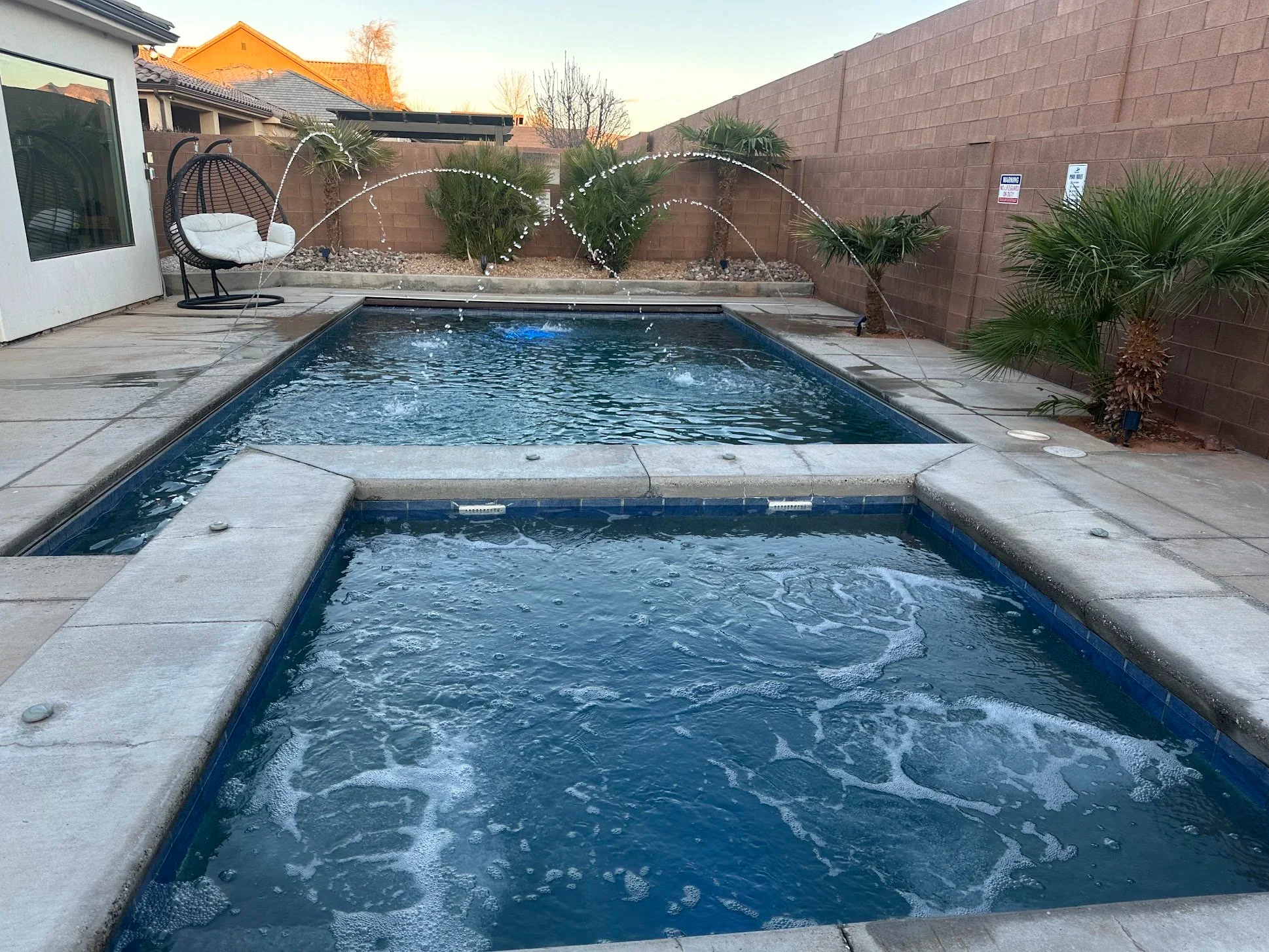 Aqua Desert backyard pool with water-feature fountains, palm trees, and a resort-style deck