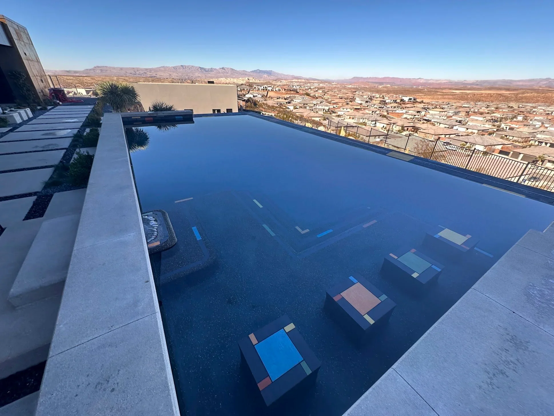 A modern Aqua Desert swimming pool with deep blue water and a tile border overlooking the Southern Utah mountains