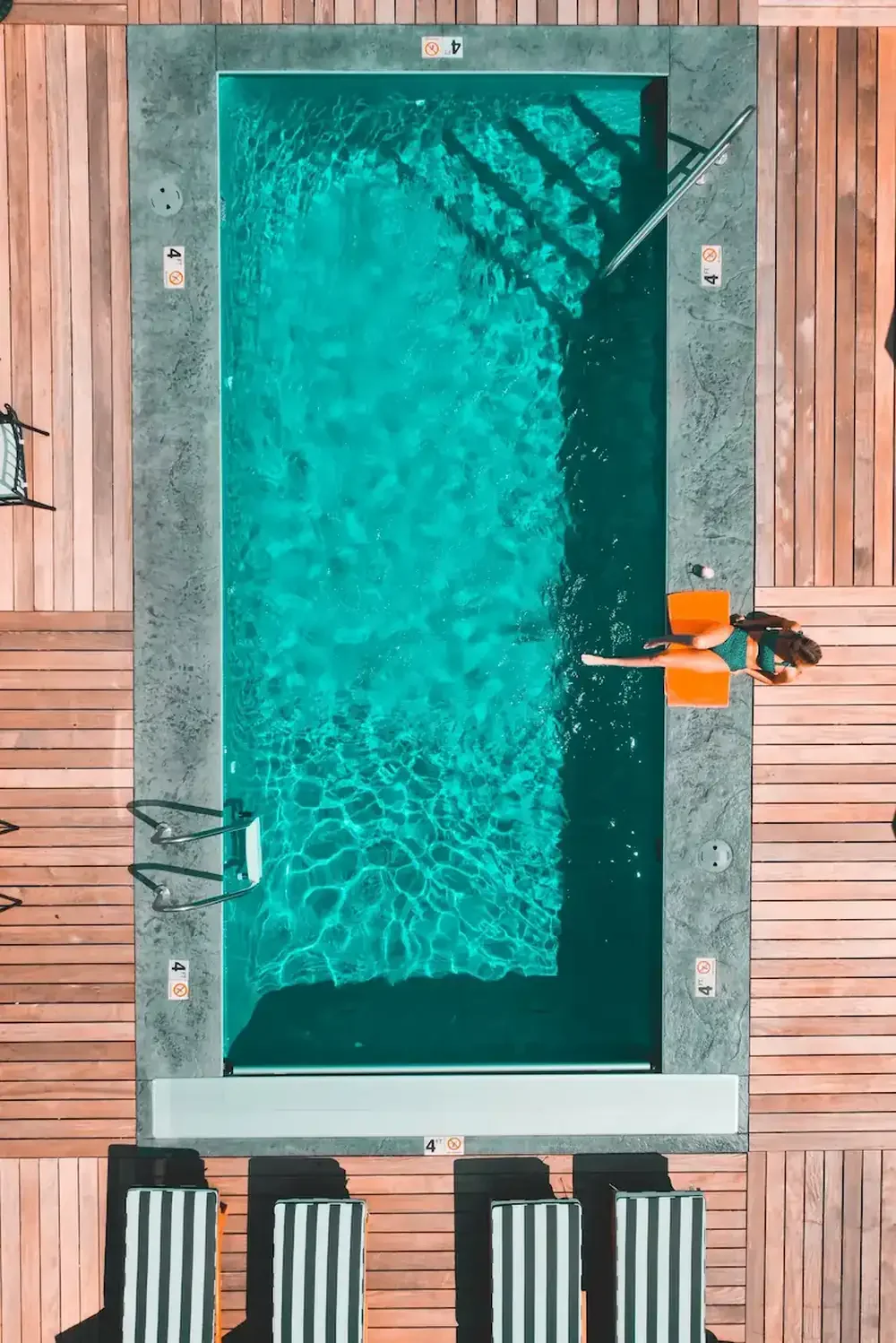 Aerial view of a person relaxing on a float in a clean pool